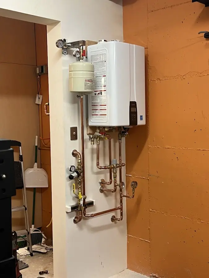 Plumbing technician inspecting water heater connections in Granville